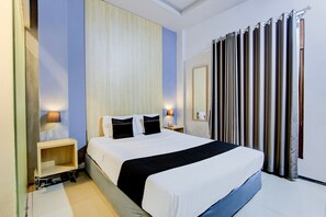 Ein Hotelzimmer mit einem Bett, Nachttischen, einem Spiegel und einem Vorhang.