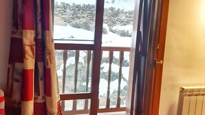 Ein Zimmer mit großem Fenster, einer hölzernen Bank und einem Heizkörper.