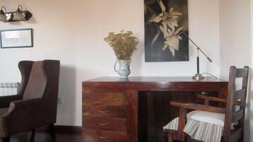 Un bureau en bois, orné d’un vase de fleurs séchées, d’une lampe et d’une chaise avec un coussin à rayures.