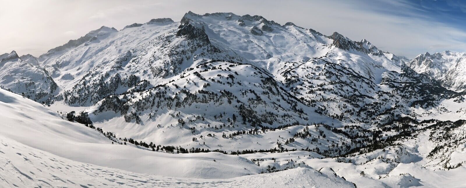 A snow-covered mountain landscape with rugged peaks and dense forest areas.