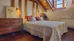 Ein Schlafzimmer mit Holzboden, einem Bett mit Patchworkdecke, einem Schminktisch und einer Wandleuchte.