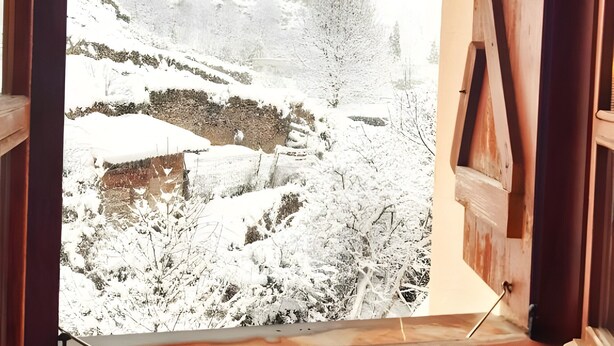 Ein Fenster mit Blick auf eine verschneite Landschaft.