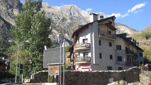 Ein steinernes Gebäude mit Balkon, umgeben von Bergen.