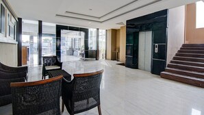 A spacious lobby with a glass wall, a reception desk, wicker chairs, and a staircase. - Luxury Deluxe DBL Retreat W/ Free WiFi and Parking (Pekanbaru)