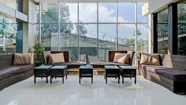 A spacious room with large windows, wicker furniture, and a view of a building with barbed wire. - Luxury Deluxe DBL Retreat W/ Free WiFi and Parking (Pekanbaru)