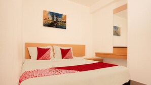 Une chambre d’hôtel avec un lit, une tête de lit, une table de chevet, un miroir et un tableau au mur.