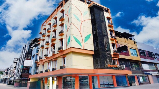 Un hôtel à plusieurs étages, doté d’un design moderne, avec des balcons et un grand panneau noir vertical qui se distingue sur la façade.