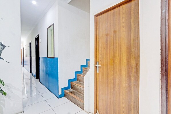 Un pasillo con una escalera, una puerta de madera y una pared con detalles azules.