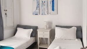 Hotellihuone, jossa on kaksi erillistä sänkyä, yöpöytä, lamppu ja seinälle ripustettu taideteos.