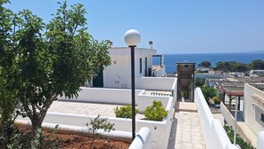 En takterrass med utsikt över havet, en lyktstolpe och en pergola.