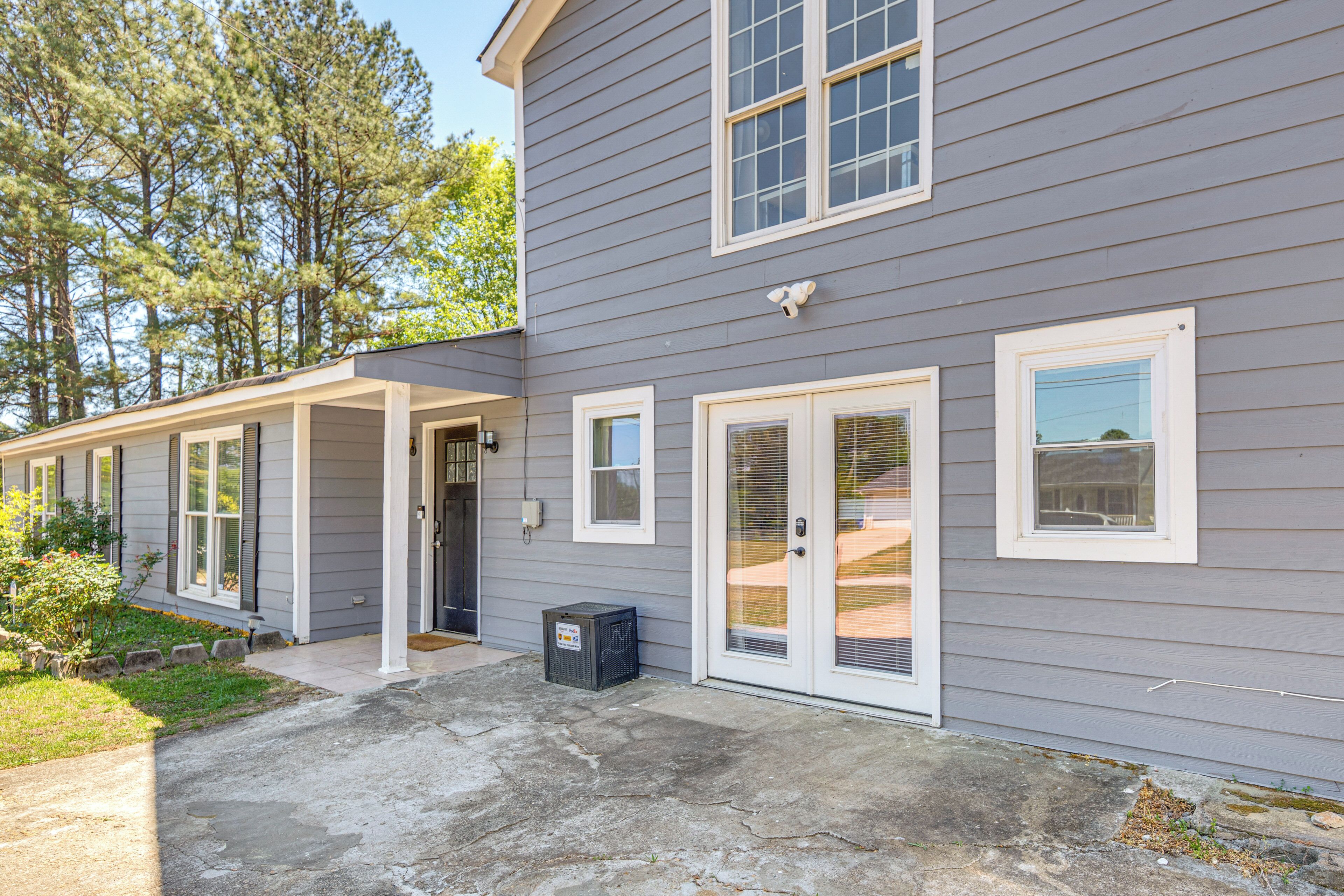 A two-story house with a covered porch, a front door, and a small air conditioning unit.