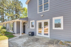 A two-story house with a covered porch, a front door, and a small air conditioning unit. - Explore ATL! Cozy Couple's Hideaway in Ellenwood (Ellenwood)