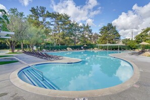 Una piscina amb gandules, una zona coberta i un jardí tancat per una tanca.