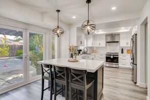 A modern kitchen with a large island, pendant lighting, and a view of the backyard. - Spacious Patio + Modern Interior: Corona Escape! (Corona)