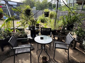 Une terrasse agrémentée de plantes en pot, une table ronde et deux chaises.
