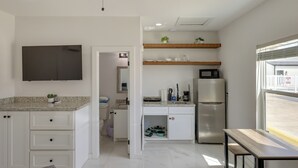 Uma cozinha moderna com armários brancos, micro-ondas embutido e geladeira.
