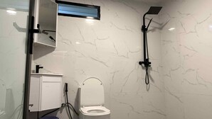 Un baño con inodoro, ducha y espejo.