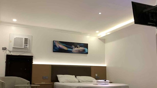 Una habitación de hotel moderna con cama, mesita de noche, silla y un cuadro en la pared.