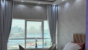 Habitación de hotel con una cama grande, vistas de la ciudad a través de una ventana y una lámpara en el techo.