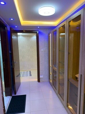 A hallway with a modern ceiling design, glass doors, and a tiled floor.