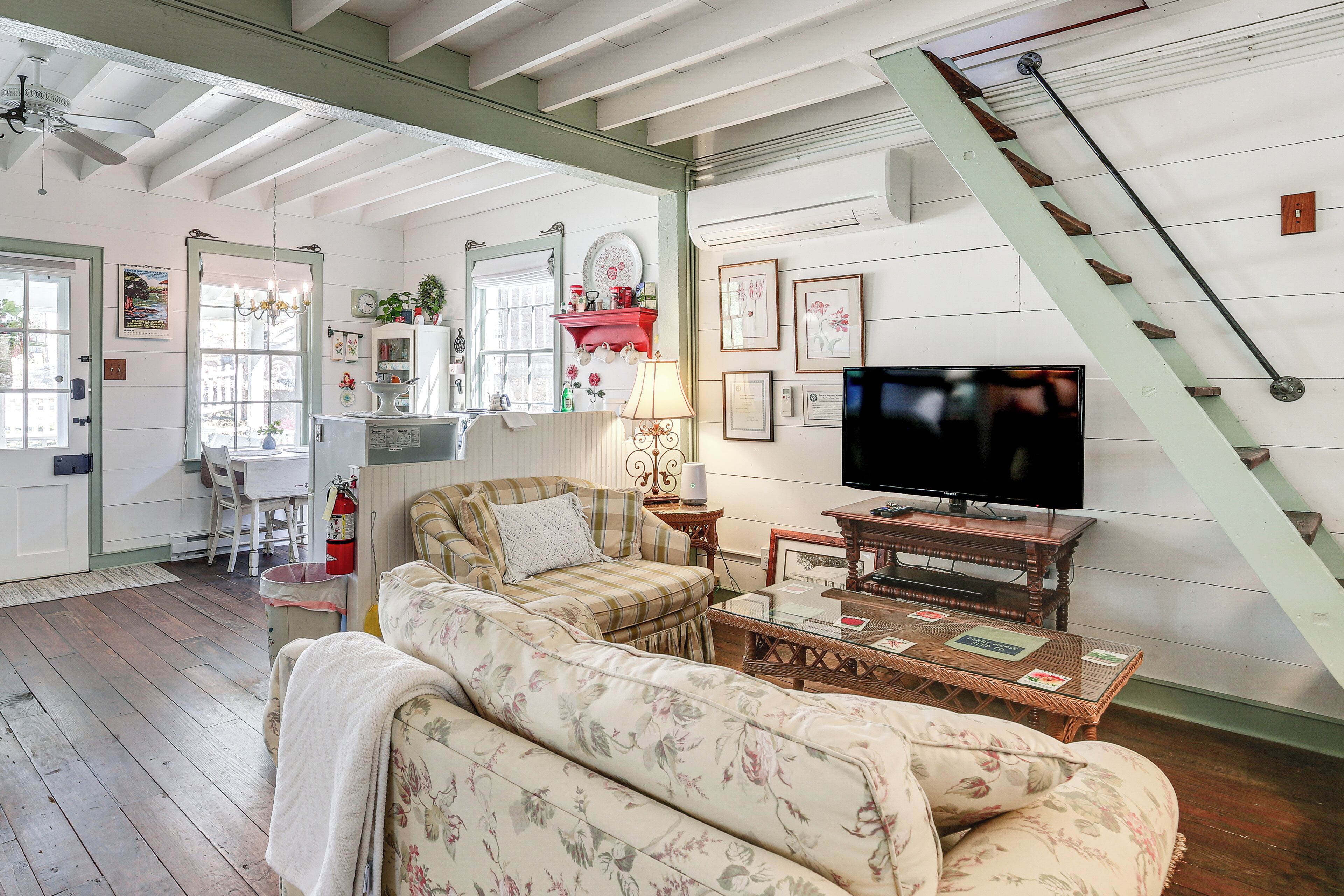 A cozy living room with a sofa, a television, and a staircase.