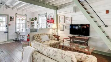 A cozy living room with a sofa, a television, and a staircase.