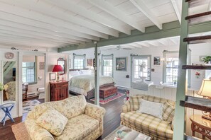A cozy room with a bed, two sofas, a small table, and a mirror.