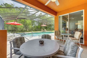 A covered outdoor seating area with a pool, chairs, and a table. - Gateway to Disney! Family-Friendly Davenport Haven (Davenport)