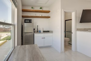 Eine moderne Küche mit Kühlschrank, Mikrowelle und Holzregalen über der Arbeitsfläche.