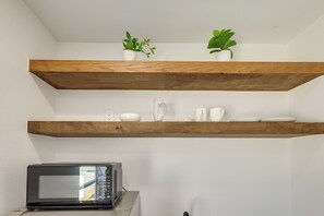 Eine Küche mit Mikrowelle, Holzregalen und Topfpflanzen.