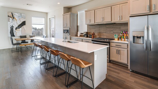 A modern kitchen with a central island, bar stools, stainless steel appliances, and wooden flooring. - Work & Play! Gem w/ Fire Pit, 3 Mi to Dtwn Dallas (Dallas)