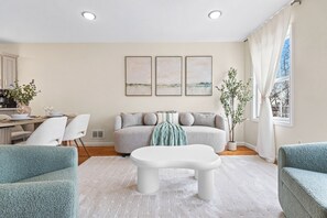 A modern living room with a sofa, two armchairs, a coffee table, and a dining area with chairs and a table. - Sleeps 20 I Metlife 10mins 6BR/4BA I 2 Free Parking & Private Deck (Jersey City)