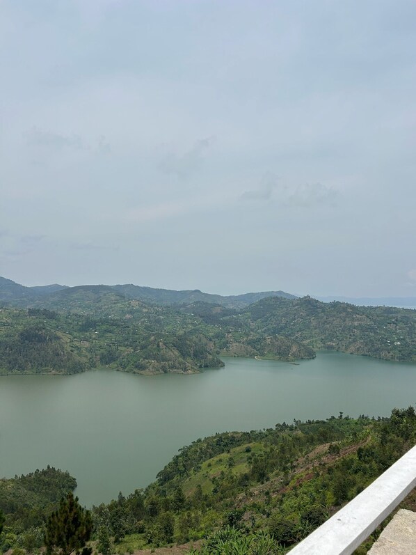 A panoramic view of a lake surrounded by hills, with a clear sky above.
