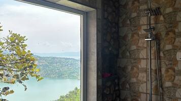 A bathroom with a shower, a window, and a stone wall.