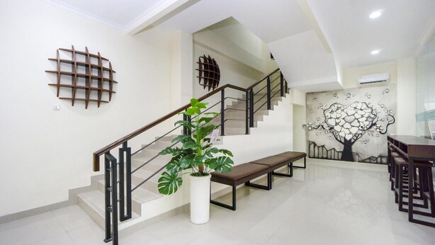 A staircase with a potted plant, a bench, and a wall with a tree mural. - Luxury Twin Stay with Free WiFi and Parking (Yogyakarta)