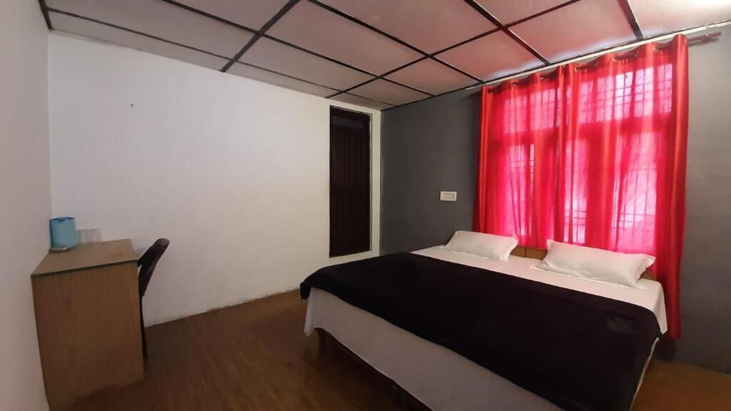A bedroom with a bed, a desk, and a door.