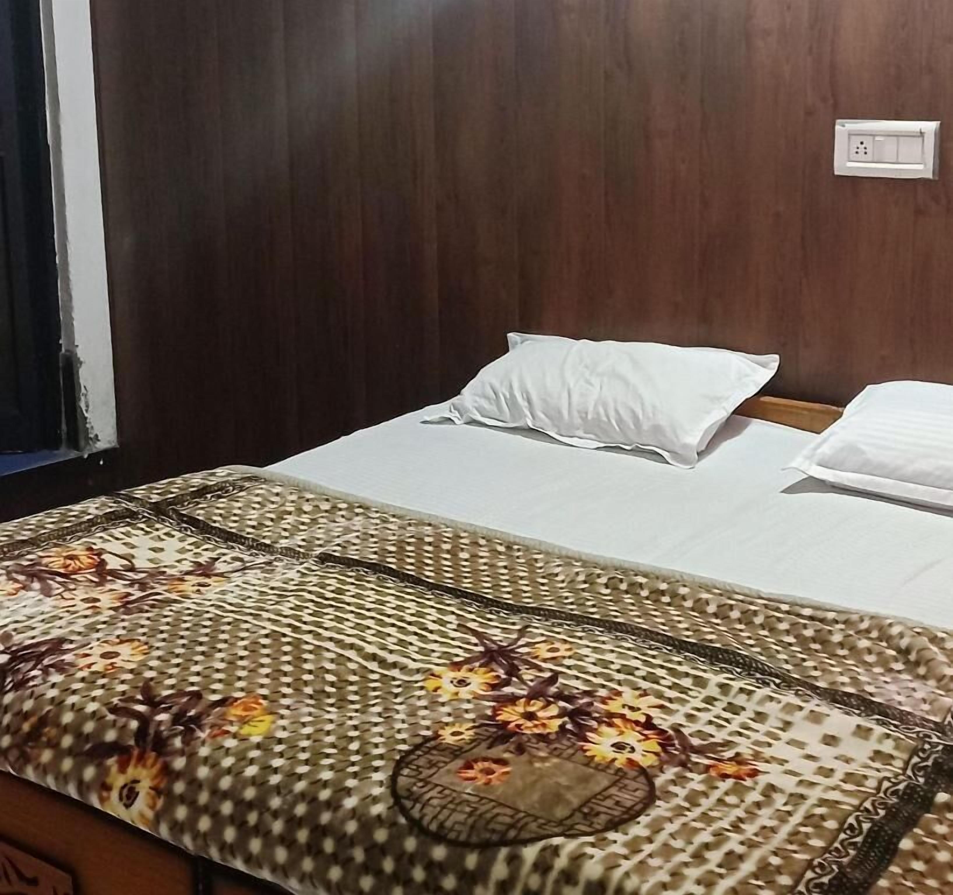 Ein Bett mit weißer Bettwäsche, einer Decke mit Blumenmuster und einem hölzernen Kopfteil.