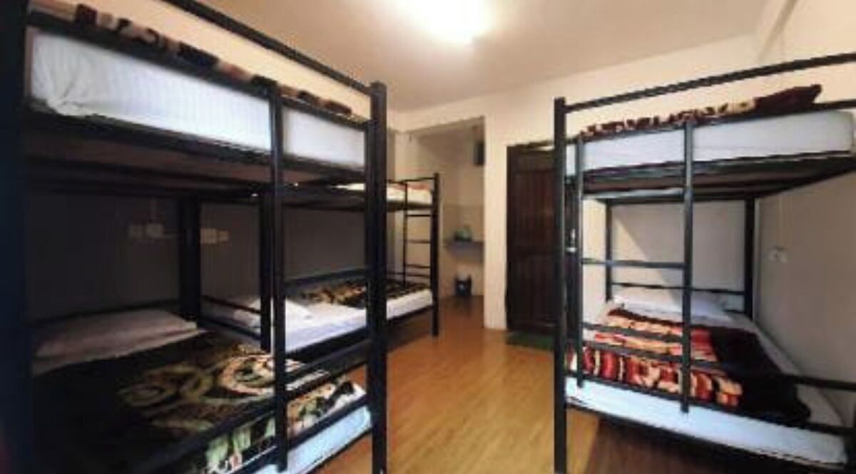 Une pièce avec des lits superposés, un plancher en bois et une porte donnant sur une autre pièce.