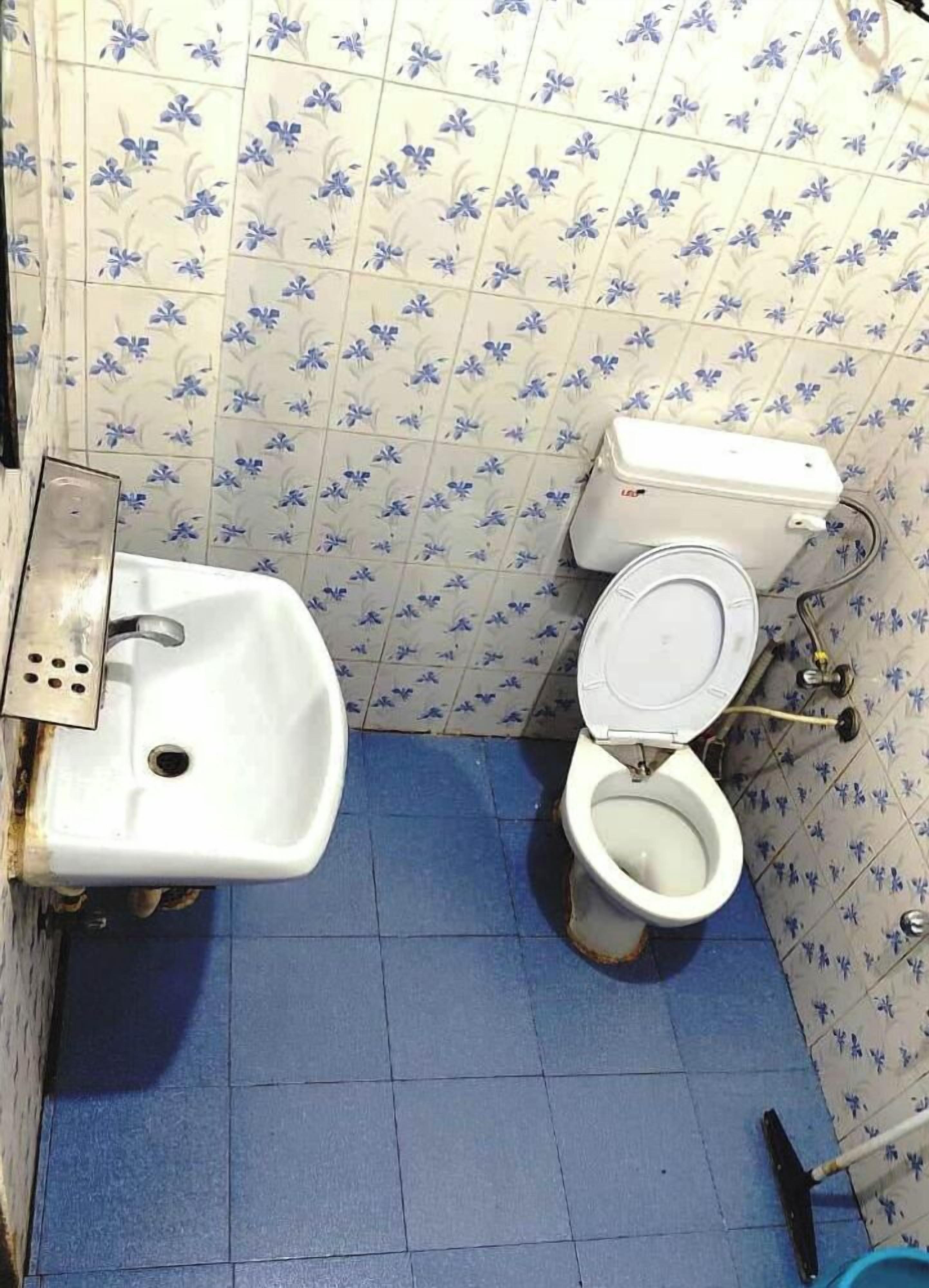 Ein Badezimmer mit Waschbecken, Toilette und blauen Fliesen.