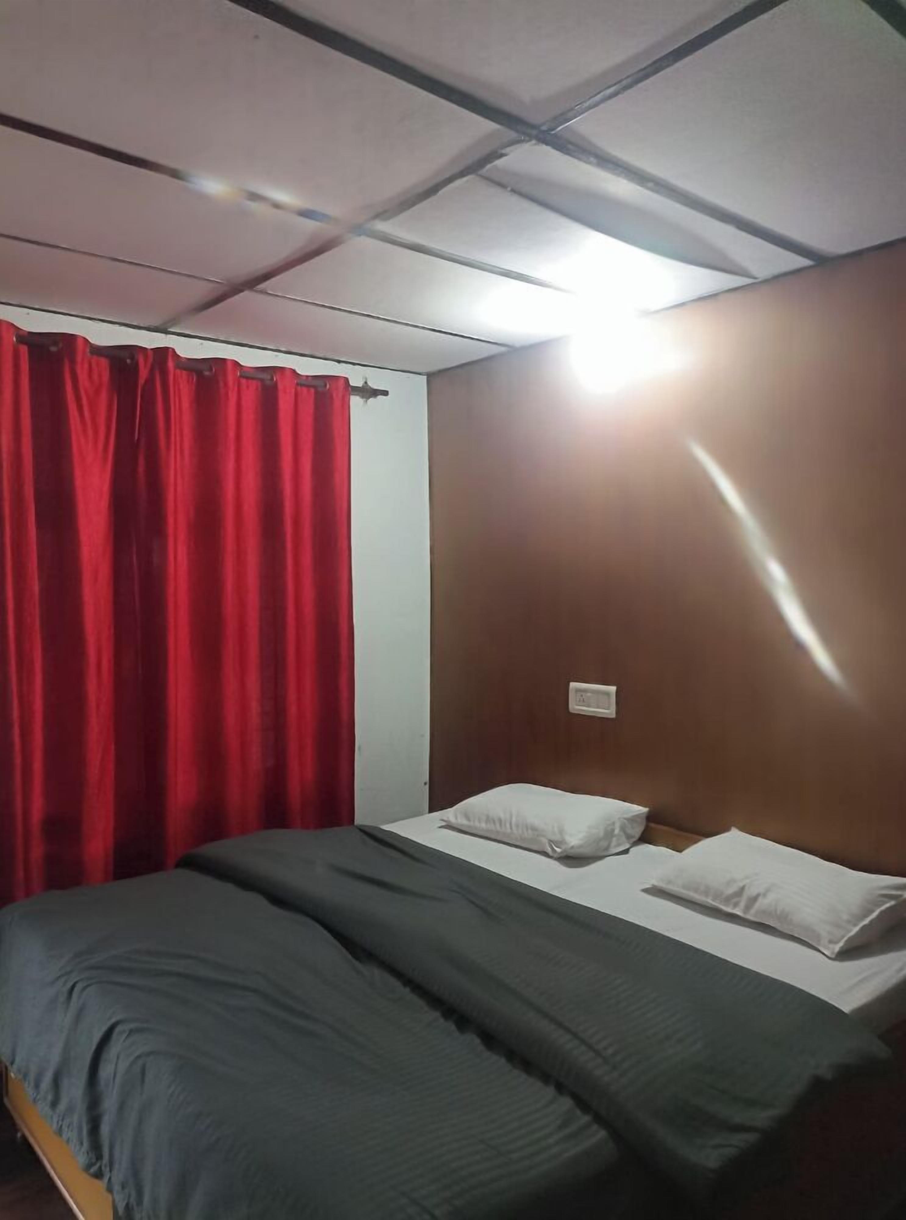 Una habitación con una cama, cortinas rojas y una pared de madera.