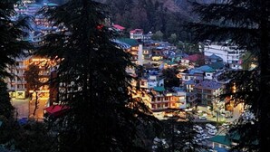 Un pueblo montañoso con edificios ubicados en un valle, rodeado de un bosque denso.