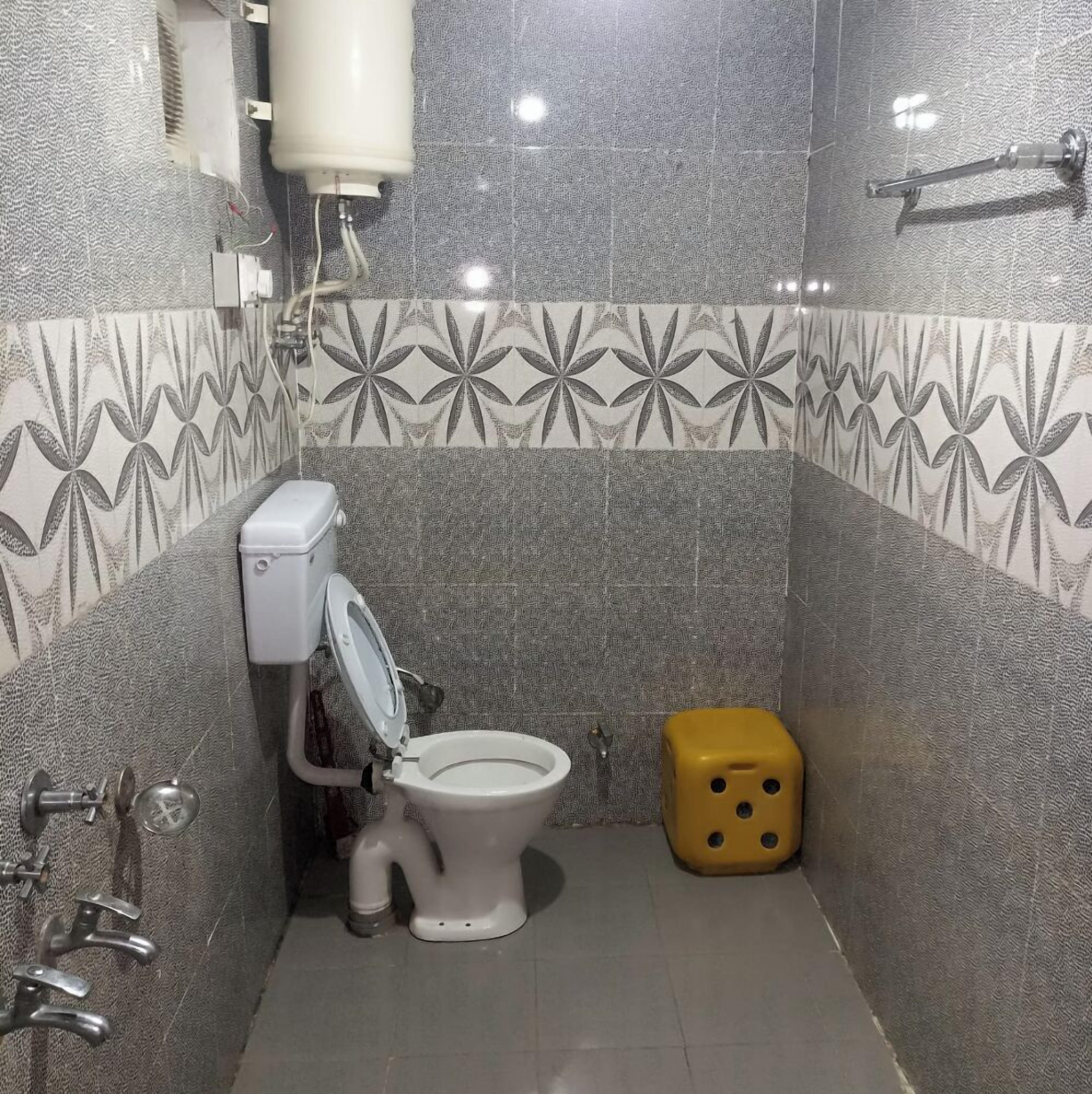 A small bathroom with a toilet, a bidet, and a yellow trash bin.