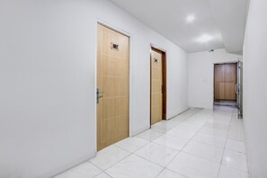 Un couloir avec deux portes en bois, l’une portant l’inscription « 102 » et l’autre dotée d’une poignée de porte visible.
