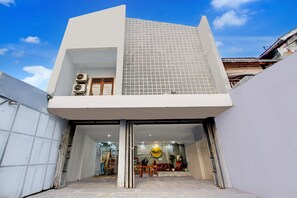 A modern building with a flat roof, large windows, and a visible interior with furniture and plants. - Family Luxury Suite W/Free WiFi and Parking (Tegal)