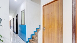Un couloir avec un escalier, une porte en bois et un mur agrémenté d’une touche de couleur bleue.