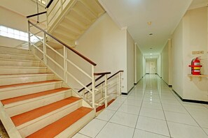 Ein Hotelkorridor mit Treppe, Feuerlöscher und Fliesenboden.