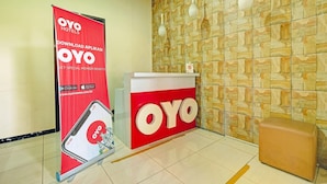 Vastaanottoalue, jossa on punainen OYO-logo, mainosbanneri, vastaanottotiski ja kuvioitu seinä.