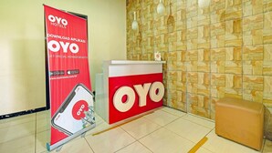 Ein Empfangsbereich mit rotem OYO-Logo, einem Werbebanner, einer Rezeption und einer Wand mit Muster.