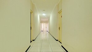 En lång, smal hall med ett klinkergolv och väggar i en ljusbeige färg.
