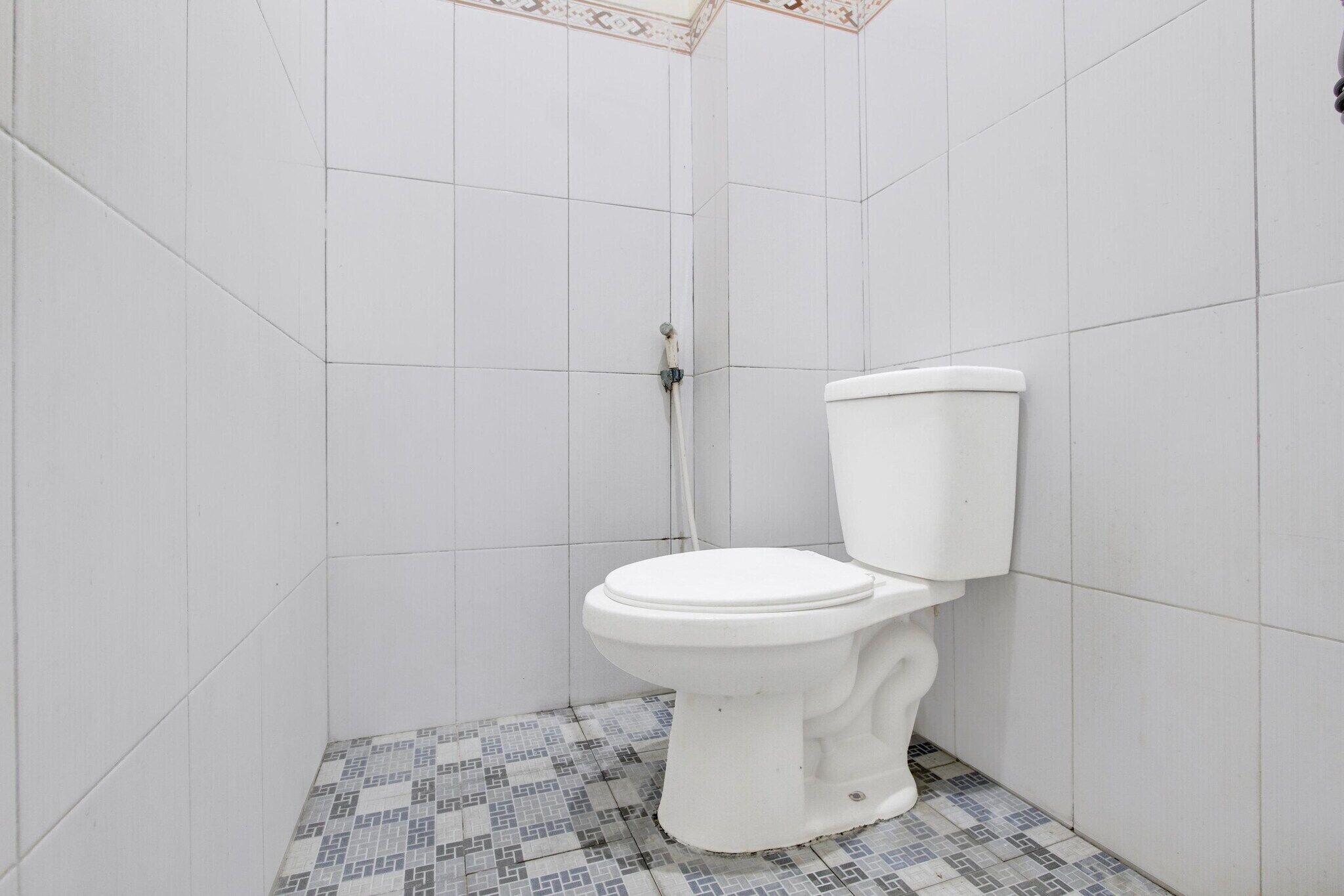 A bathroom with white tiled walls and a patterned floor.